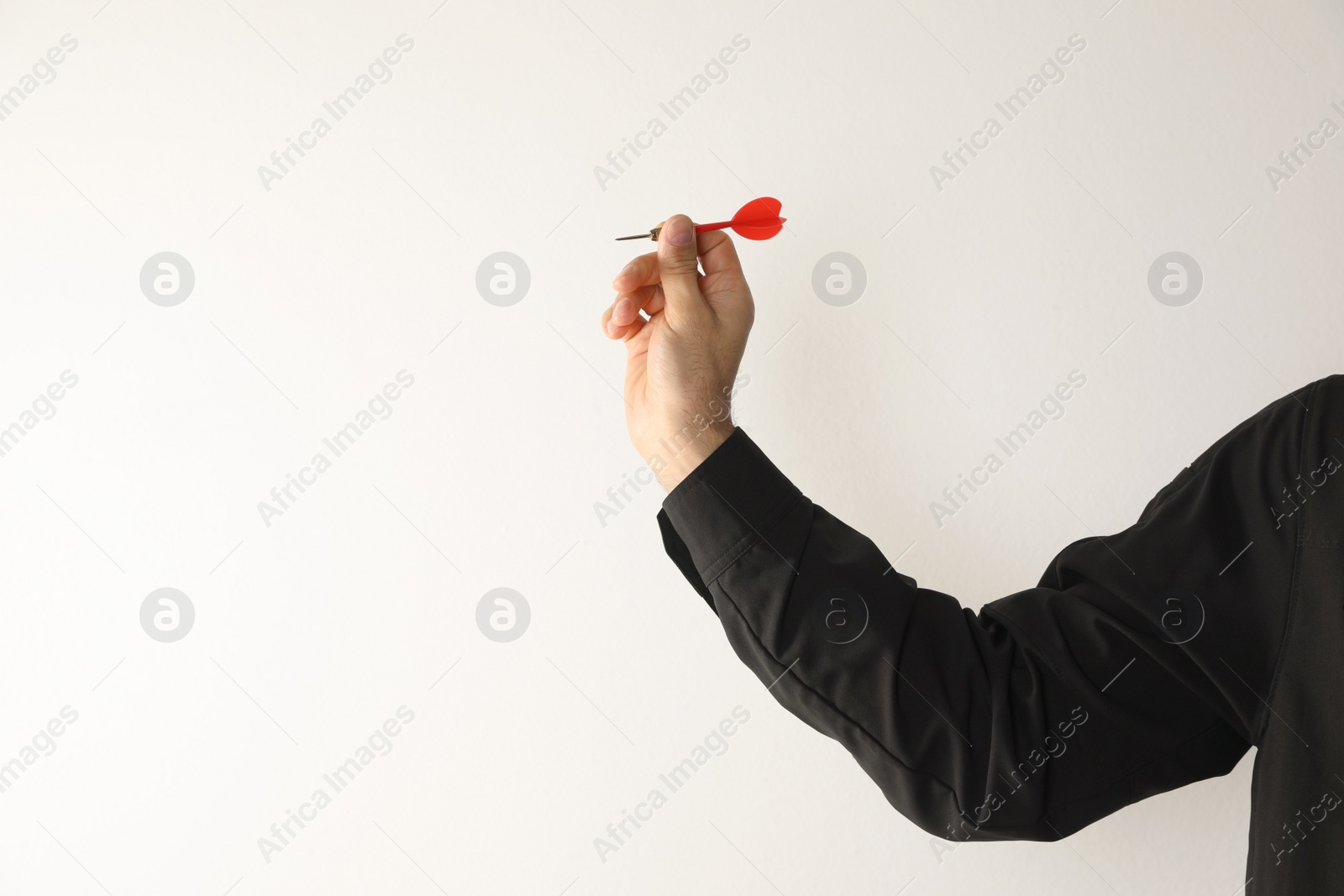Photo of Man holding red dart on light background, closeup. Space for text