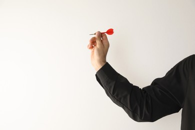 Photo of Man holding red dart on light background, closeup. Space for text