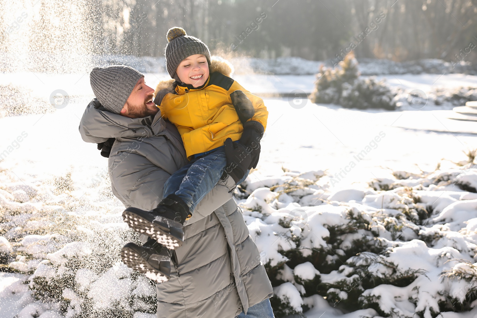 Photo of Family portrait of happy father and his son in sunny snowy park. Space for text