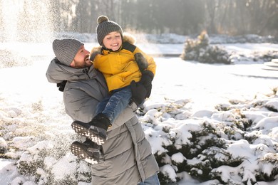 Photo of Family portrait of happy father and his son in sunny snowy park. Space for text