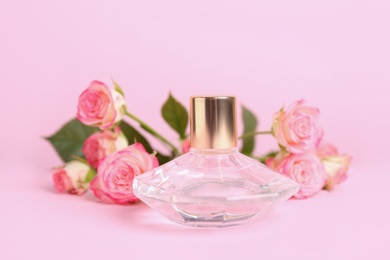 Photo of Bottle of luxury perfume and roses on pink background