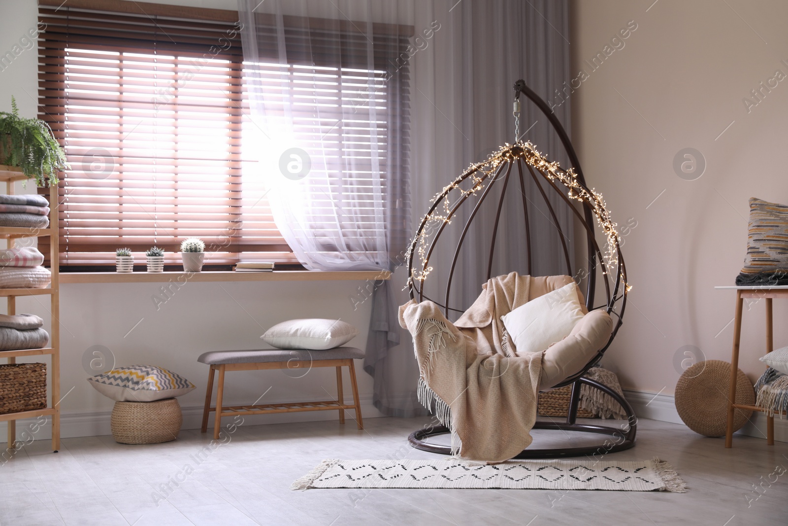 Photo of Cozy hanging chair with fairy lights in modern living room. Interior design