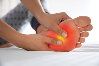 Image of Woman suffering from foot pain at home, closeup 