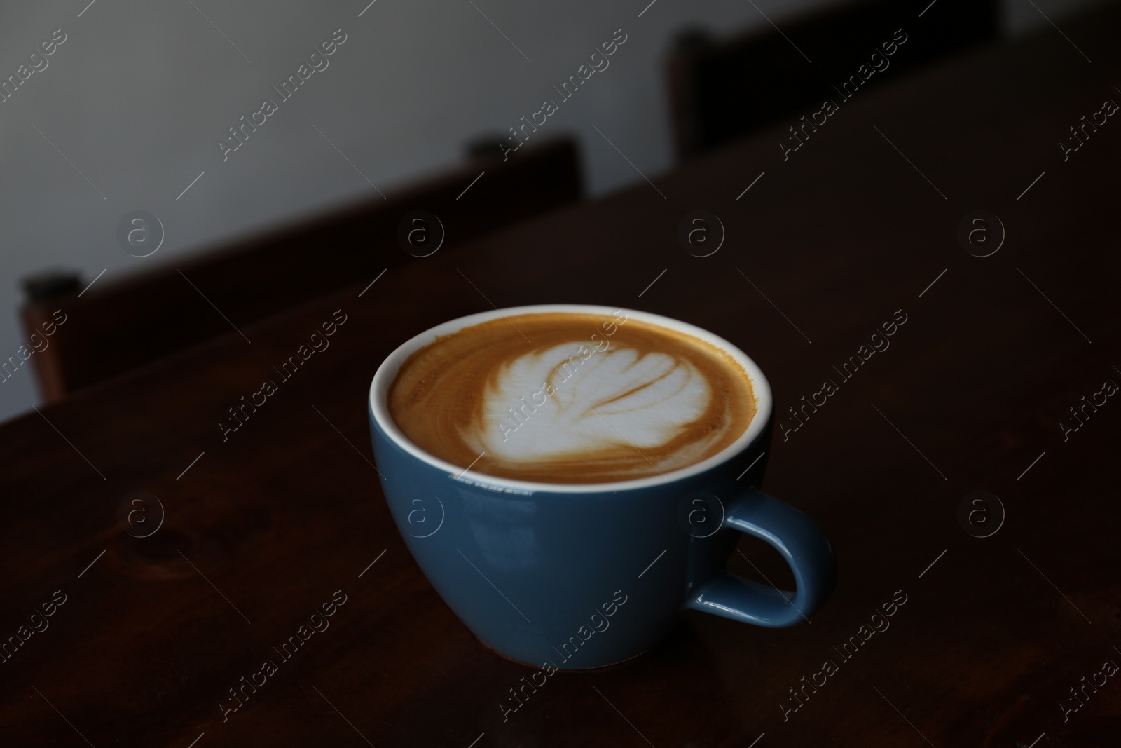 Photo of Cup of aromatic coffee on wooden table in cafe