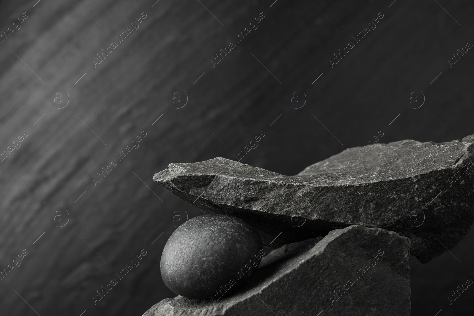 Photo of Presentation for product. Podium made of different stones on grey textured background. Space for text