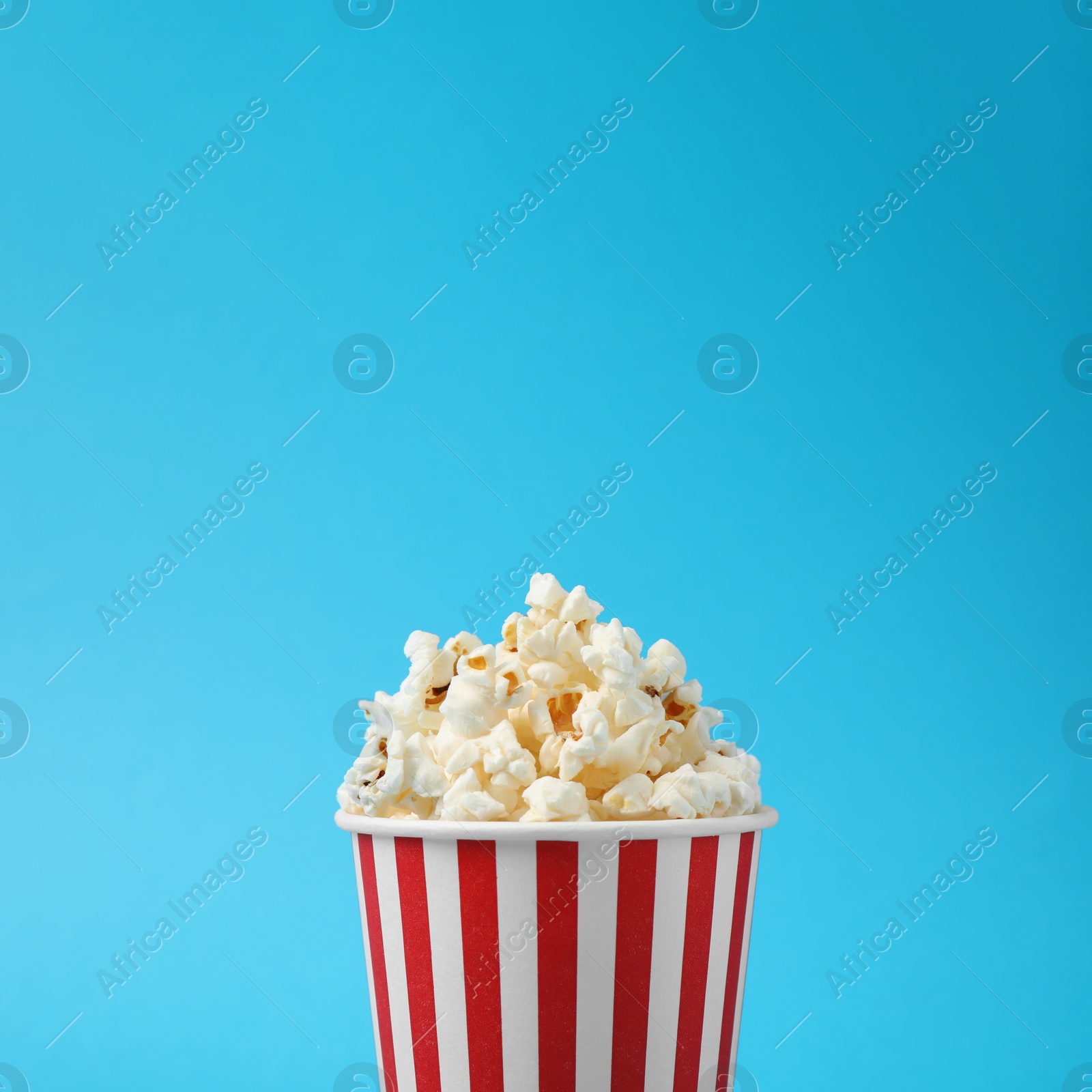 Photo of Delicious popcorn on light blue background, closeup