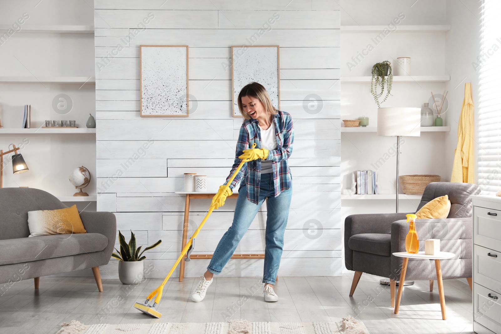 Photo of Woman with mop singing while cleaning at home