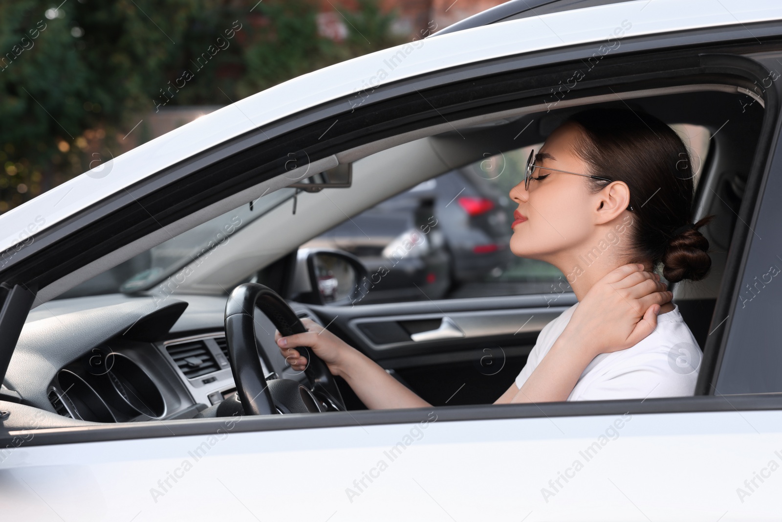 Photo of Young woman suffering from neck pain in her car