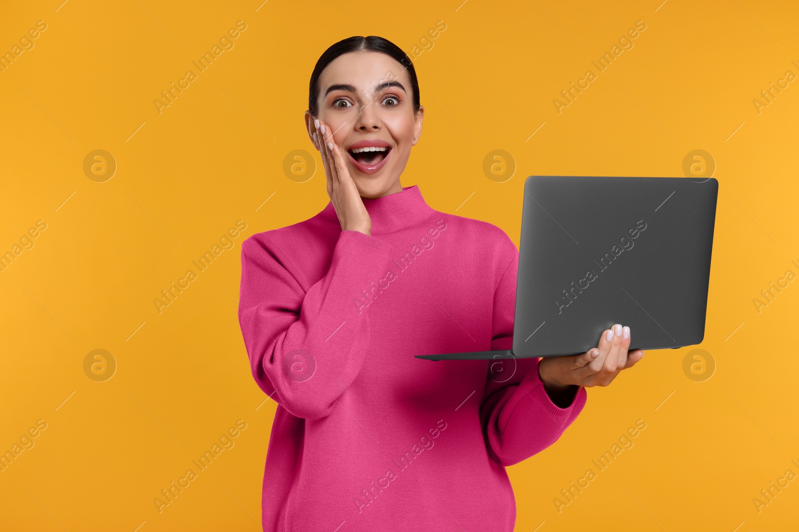 Photo of Emotional woman with laptop on orange background