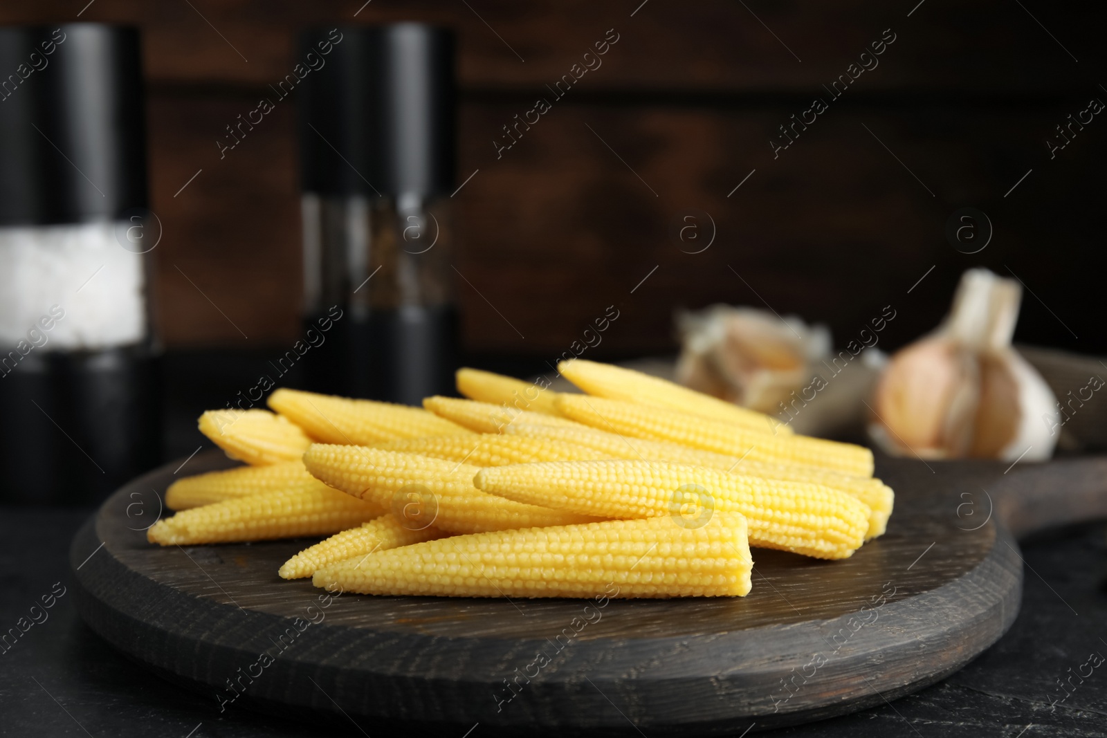 Photo of Fresh baby corn cobs served on black table