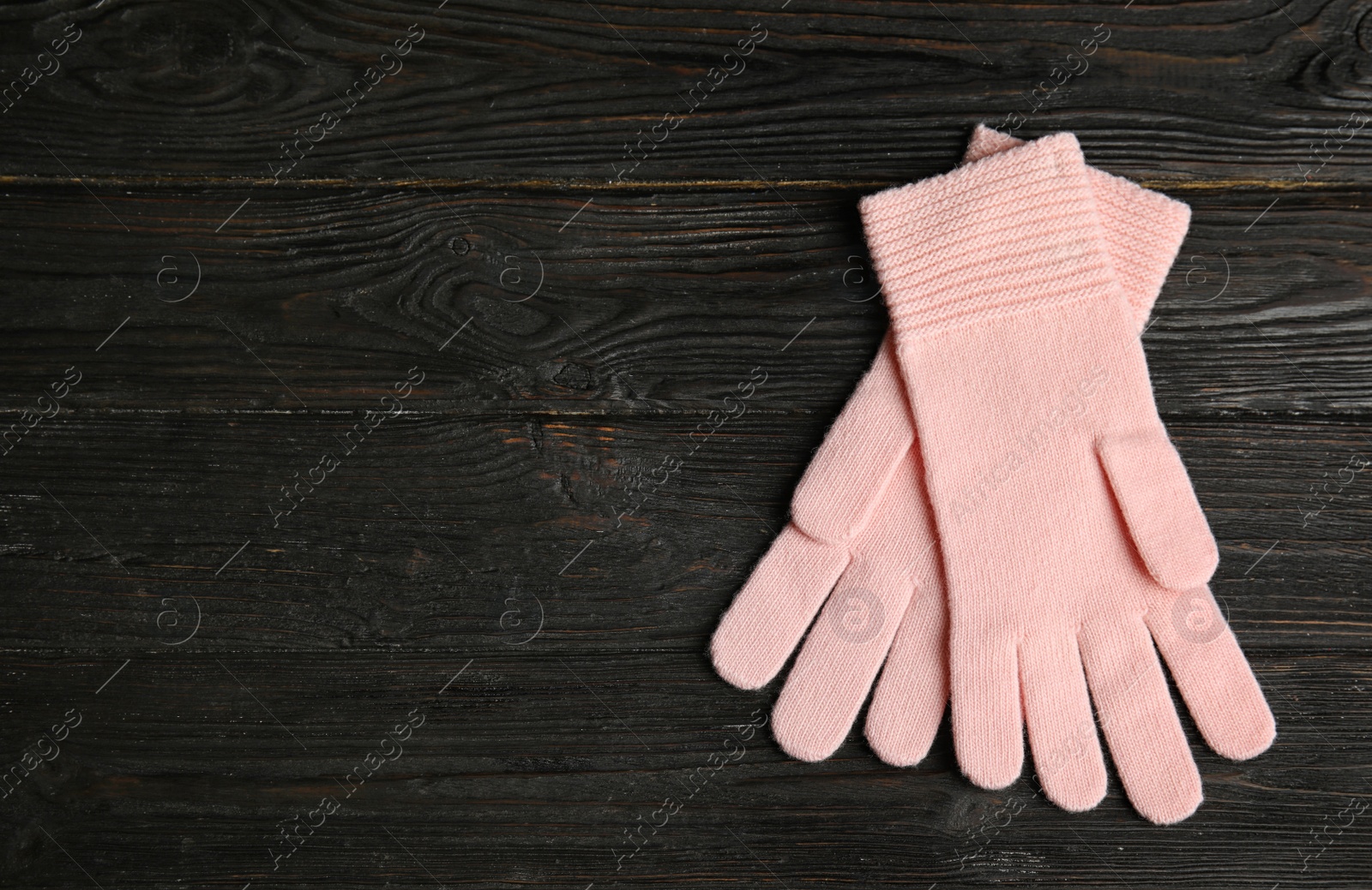 Photo of Stylish pink gloves on dark wooden background, top view with space for text. Autumn clothes