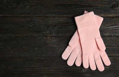 Photo of Stylish pink gloves on dark wooden background, top view with space for text. Autumn clothes