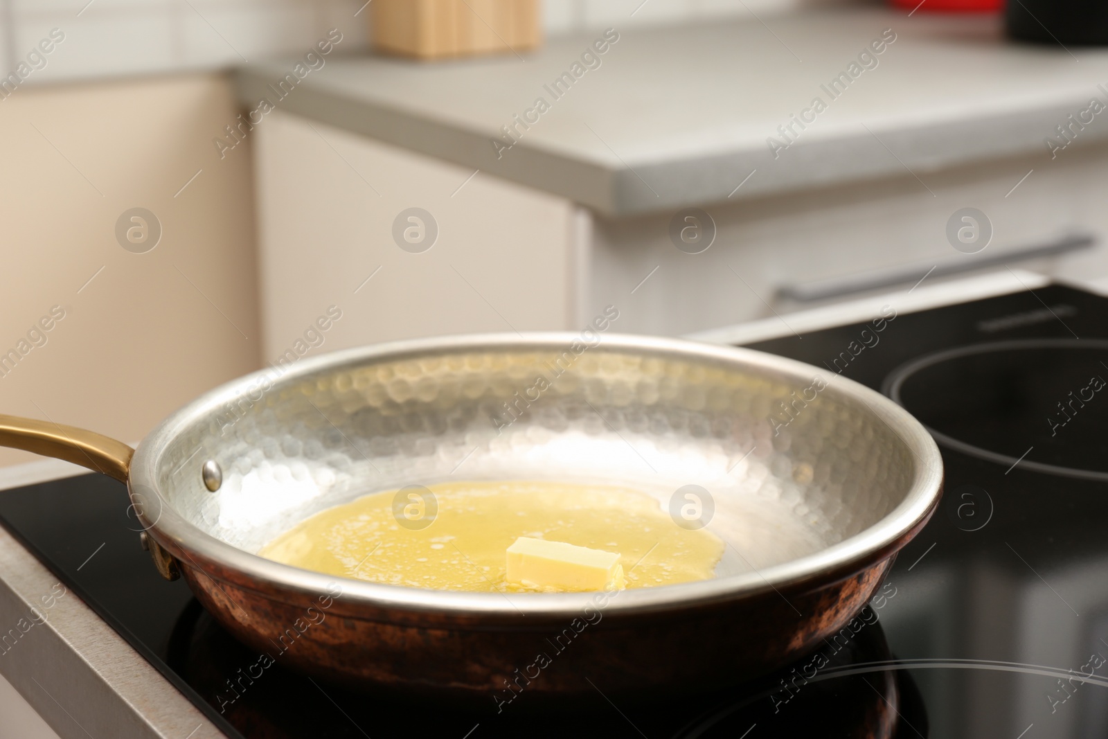 Photo of Frying pan with melted butter on stove in kitchen