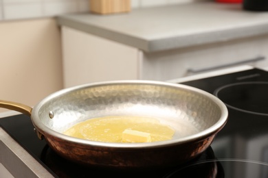 Frying pan with melted butter on stove in kitchen