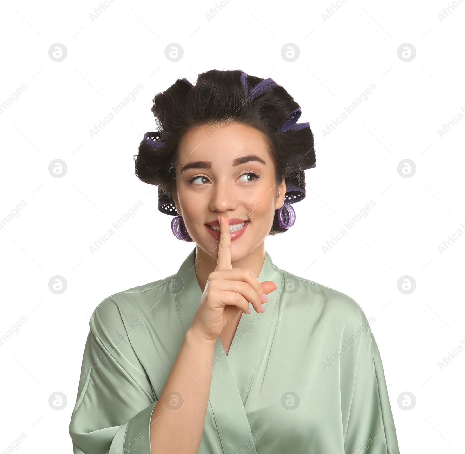 Photo of Happy young woman in silk bathrobe with hair curlers on white background