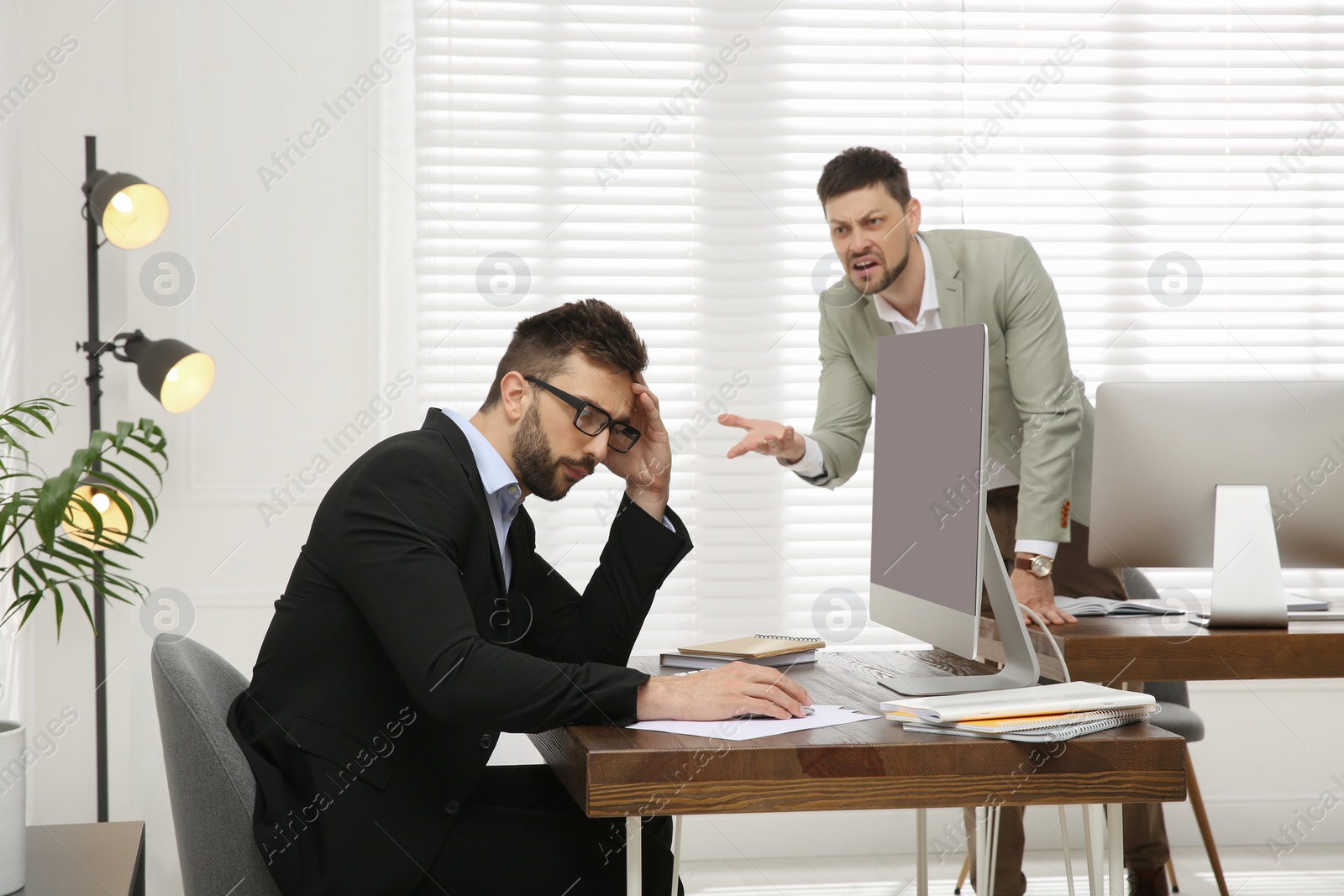 Photo of Boss screaming at employee in office. Toxic work environment