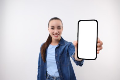 Photo of Young woman showing smartphone in hand on white background, selective focus. Mockup for design