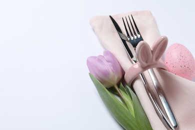 Cutlery set, Easter egg and tulip on white background, space for text. Festive table setting