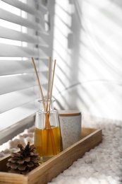 Photo of Reed air freshener and pine cone on window sill indoors