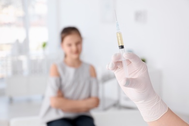 Photo of Doctor with syringe and child on background. Vaccination day