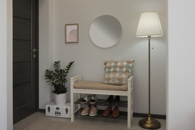 Stylish hallway room interior with bench, shoes and round mirror