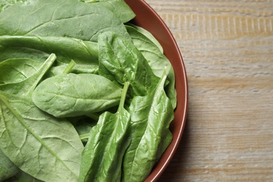 Photo of Bowl with fresh green healthy spinach on wooden table, top view