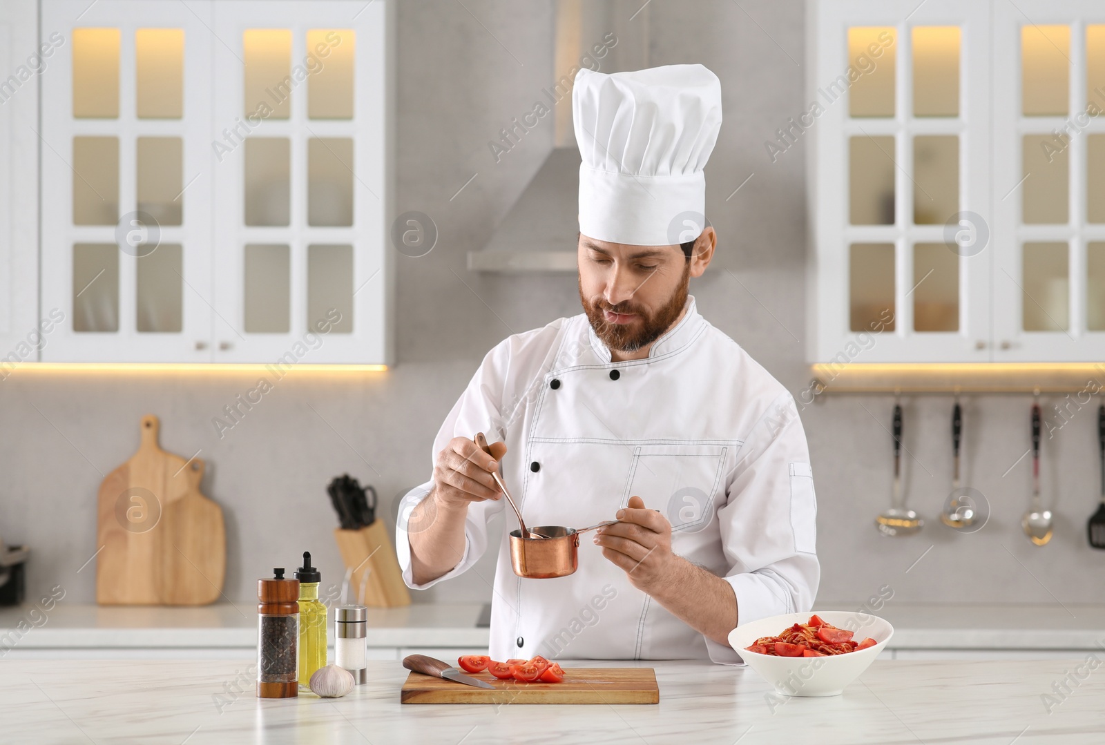 Photo of Professional chef making sauce at marble table in kitchen