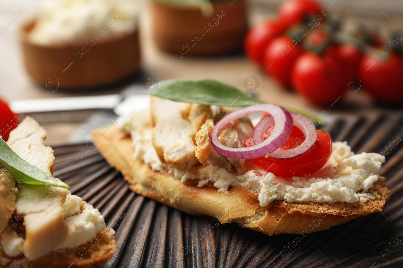 Photo of Board with delicious chicken bruschetta on table, closeup