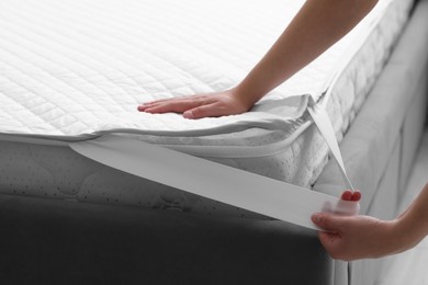 Photo of Woman putting protector on mattress, closeup view
