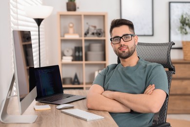 Photo of Happy young programmer working at desk in office