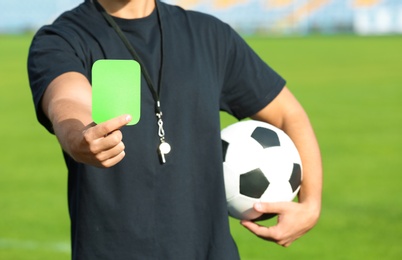 Photo of Football referee showing green card at stadium, closeup