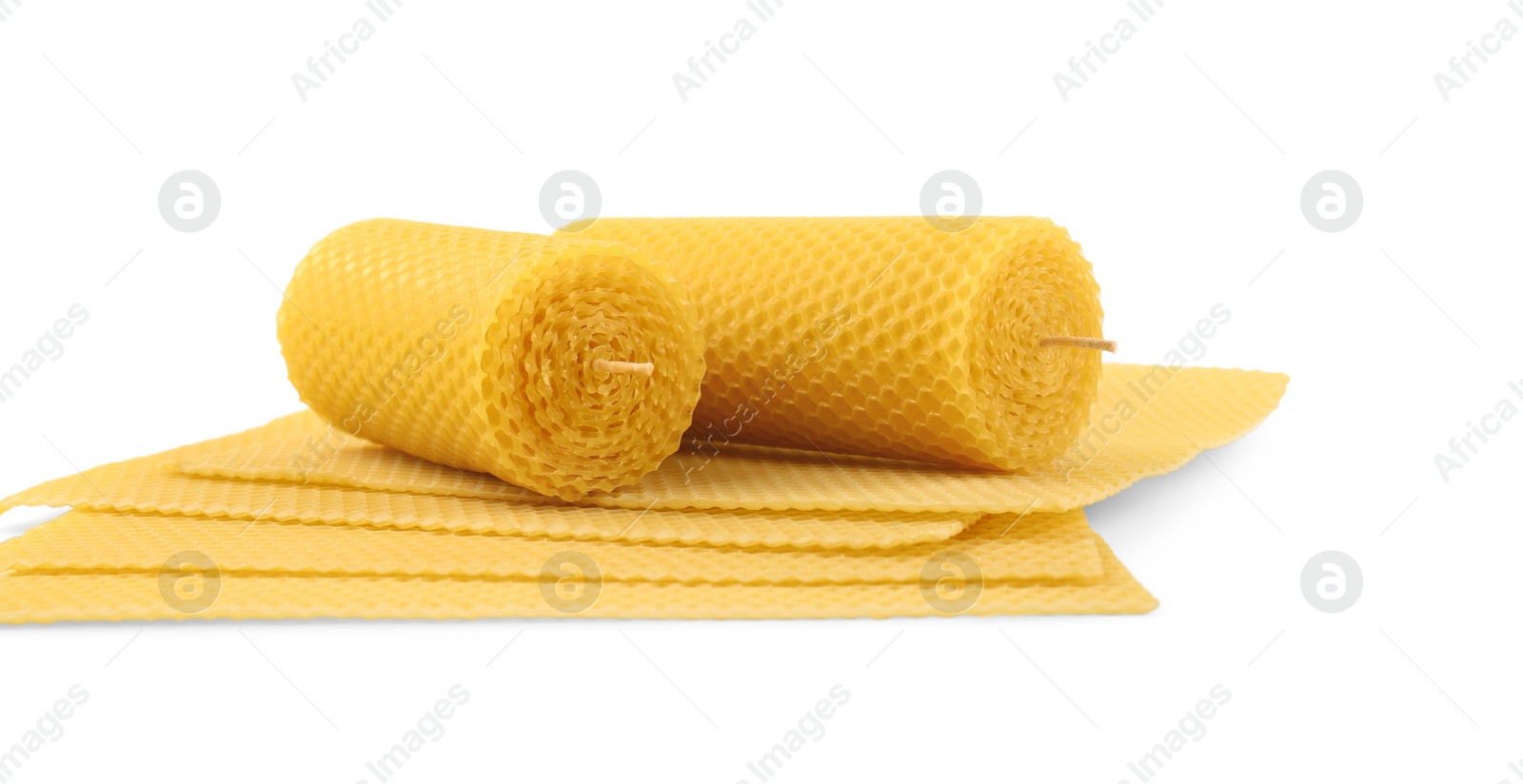 Photo of Stylish elegant beeswax candles and wax sheets isolated on white