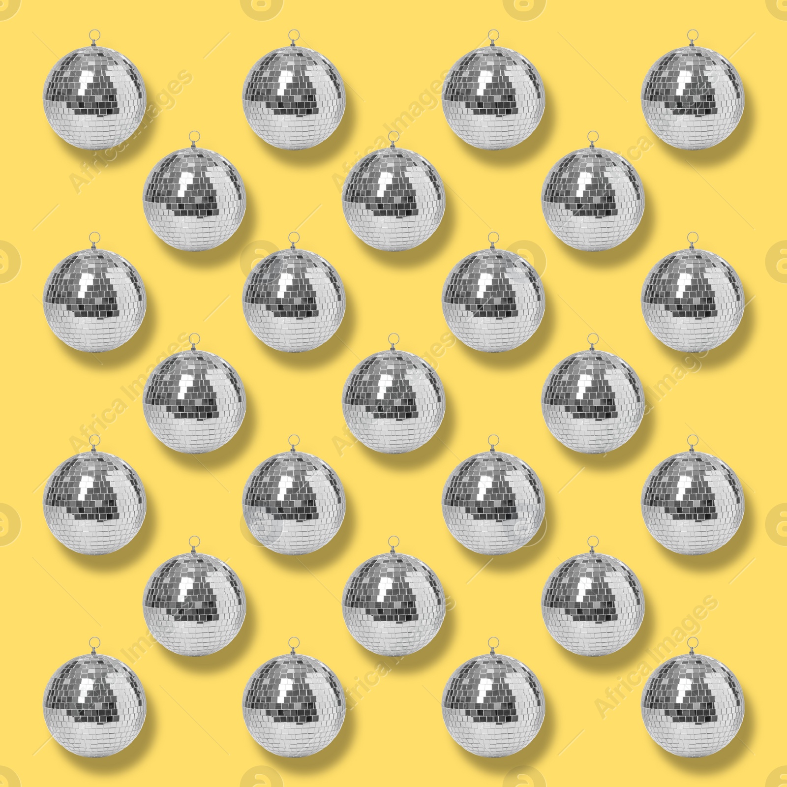 Image of Many shiny disco balls on yellow background, flat lay