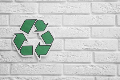 Photo of Paper recycling symbol on brick wall. Space for text