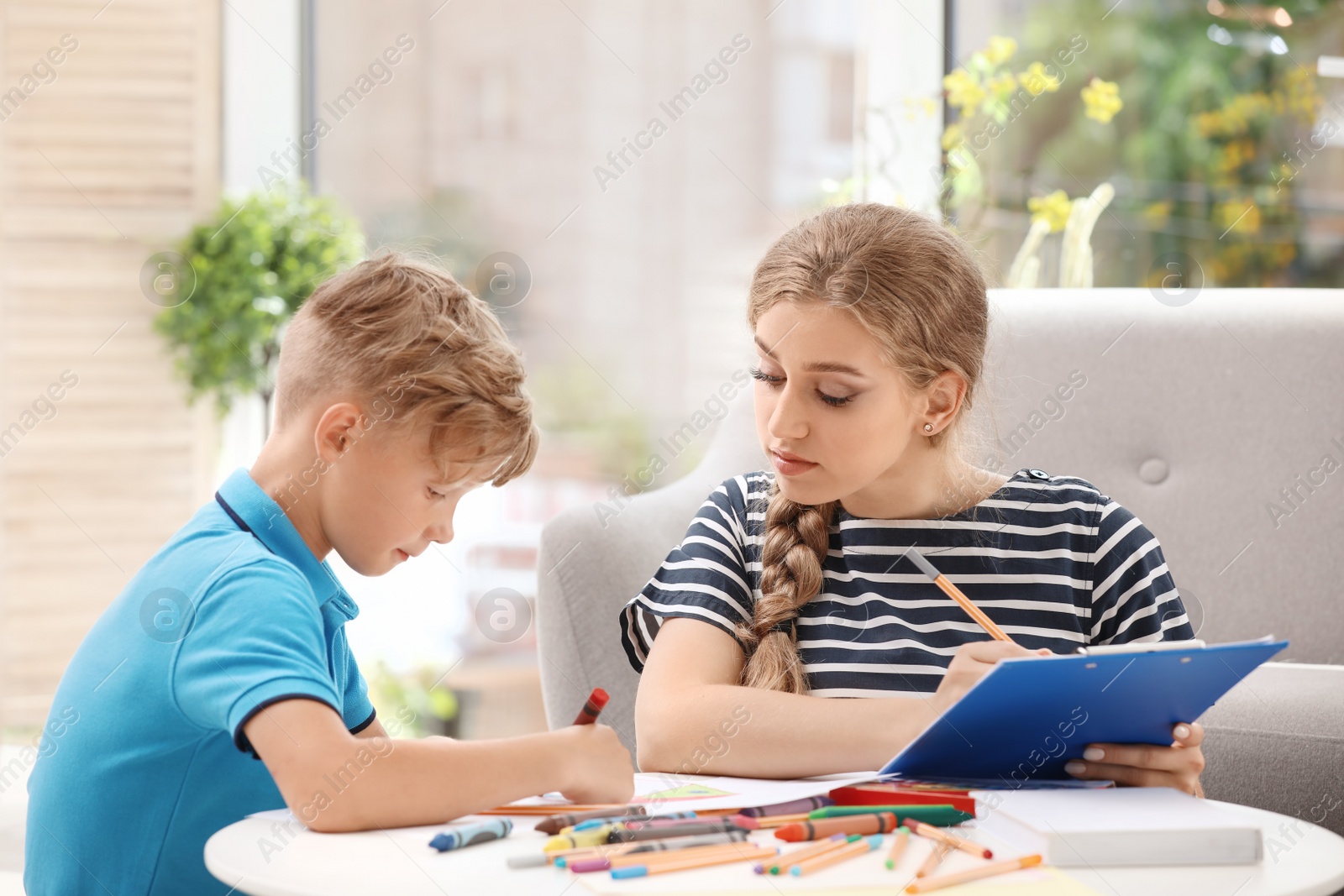 Photo of Young female psychologist working with little child in office