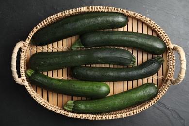 Basket with green zucchinis on black slate table, top view