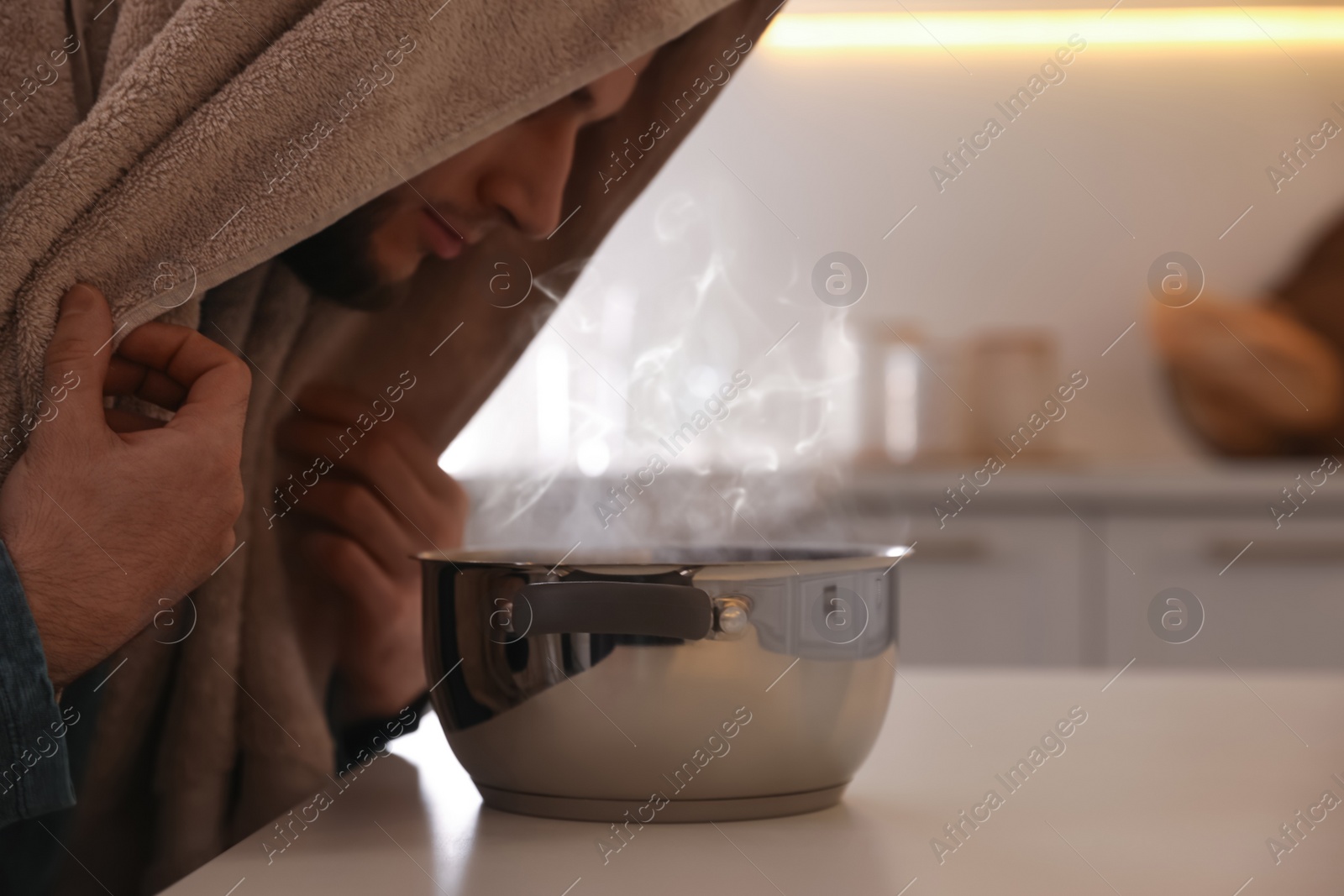 Photo of Man taking treatments at table indoors. Steam inhalation