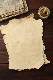 Photo of Sheets of old parchment paper, vintage book and candle on wooden table, flat lay