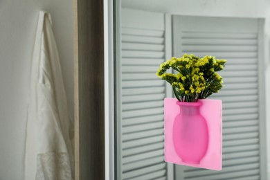 Photo of Silicone vase with beautiful yellow flowers on mirror in room, space for text