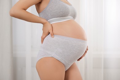 Photo of Pregnant woman in comfortable maternity underwear indoors, closeup