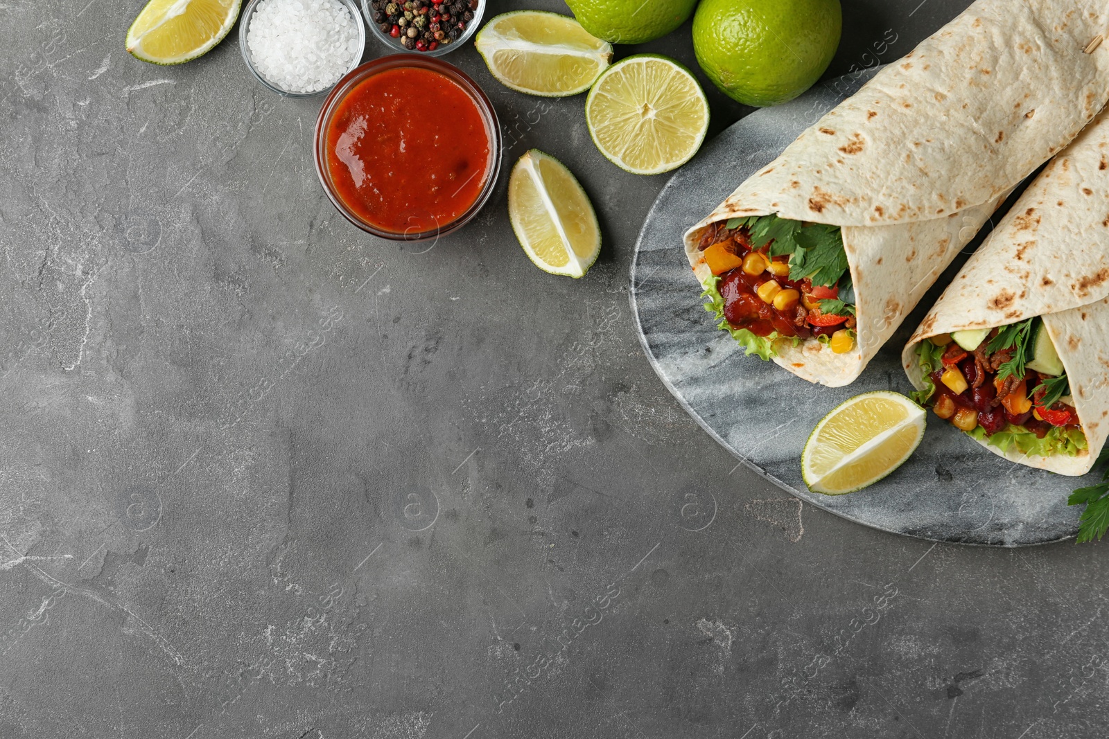 Photo of Board with delicious meat tortilla wraps on grey table, flat lay. Space for text