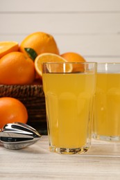 Tasty freshly made orange juice on white wooden table