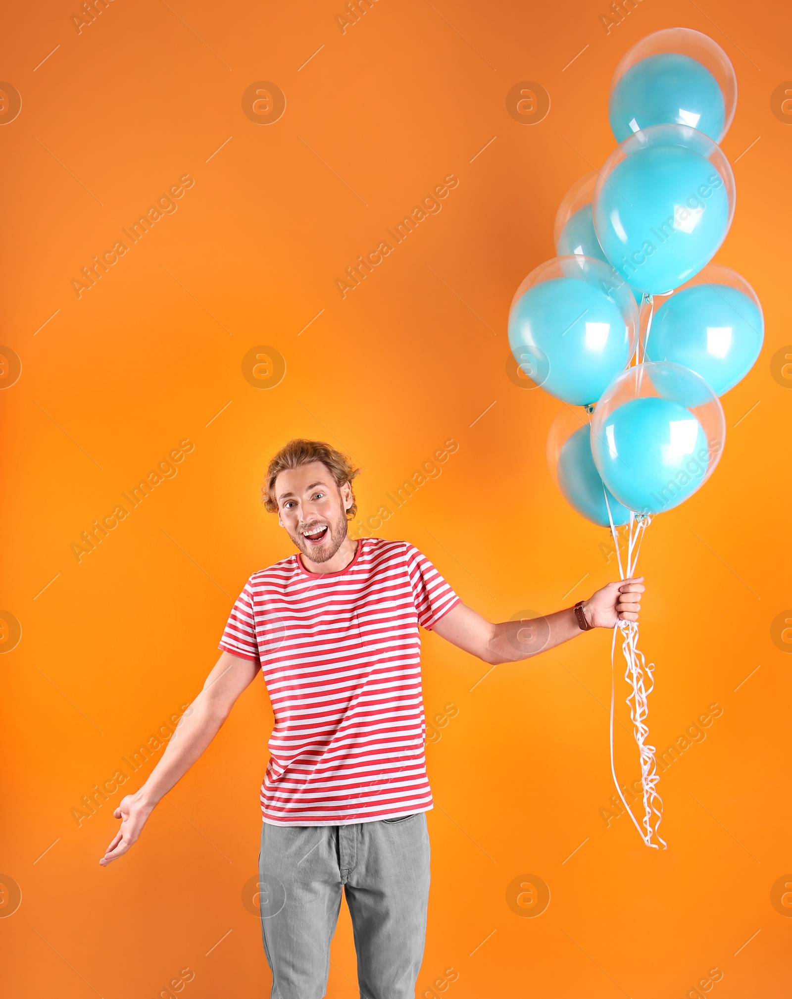 Photo of Young man with air balloons on color background