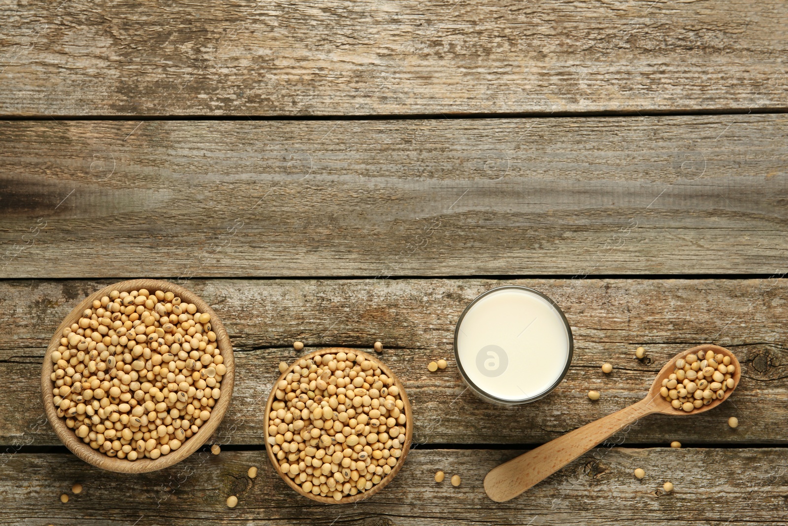 Photo of Glass with fresh soy milk and grains on wooden table, flat lay. Space for text