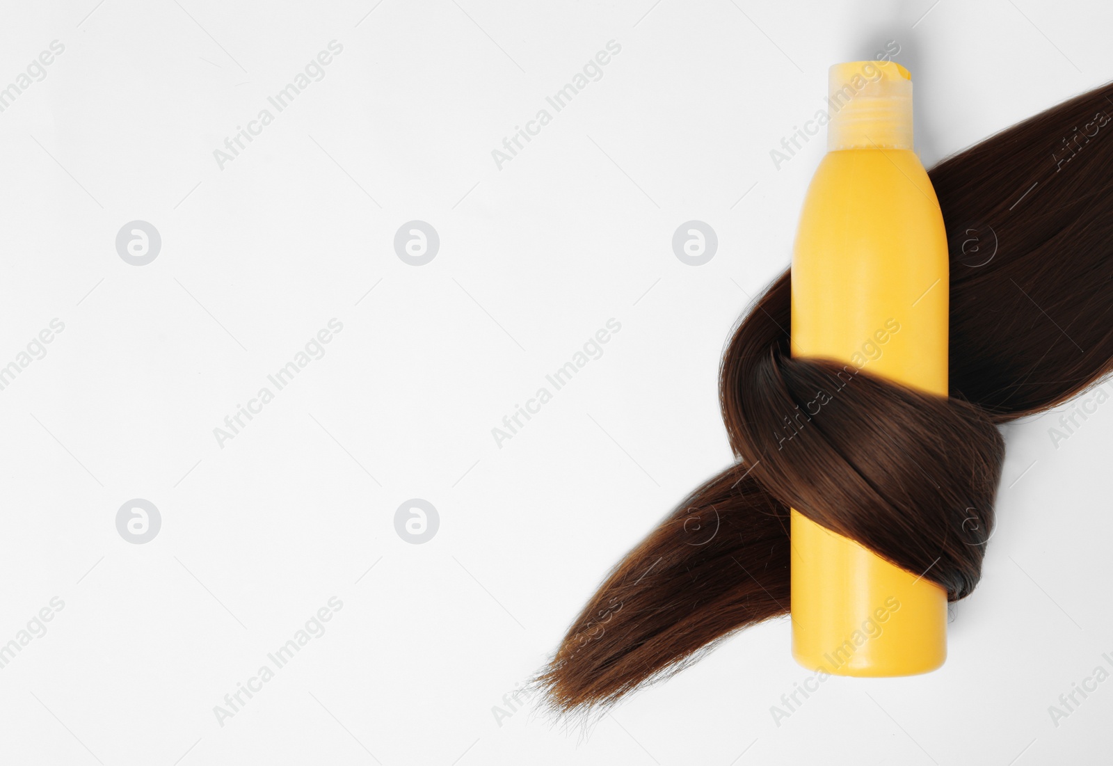 Photo of Shampoo bottle wrapped in lock of hair isolated on white, top view. Natural cosmetic products