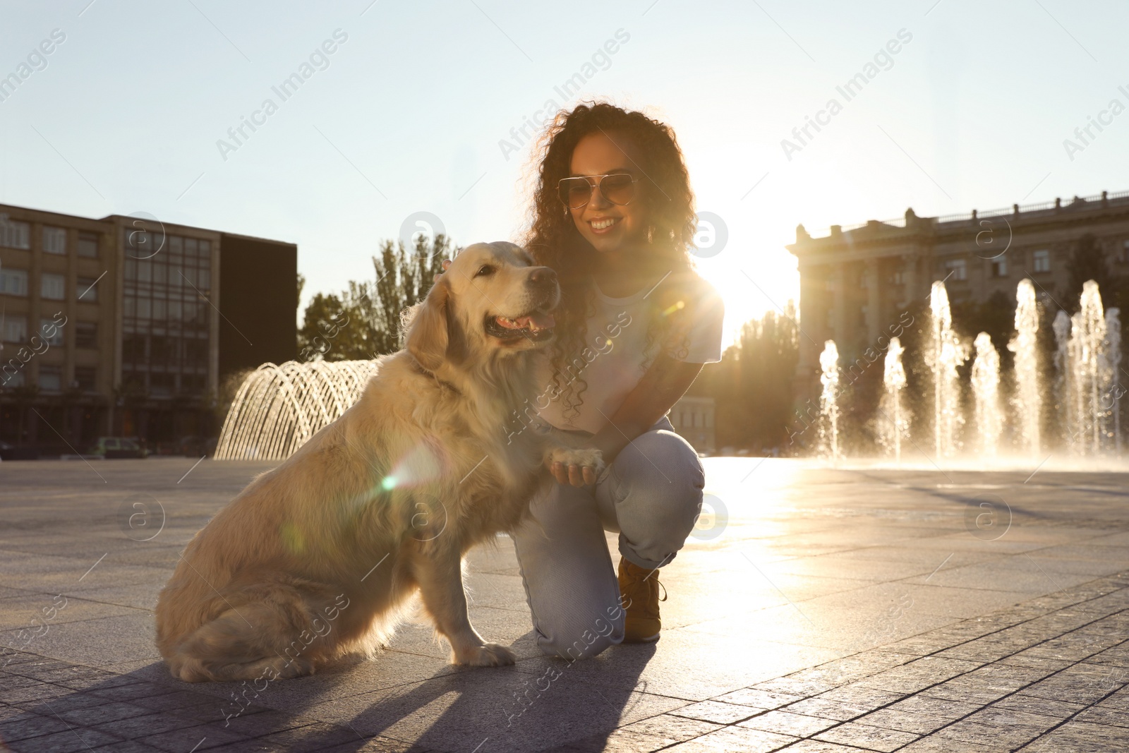 Photo of Young African-American woman and her Golden Retriever dog outdoors