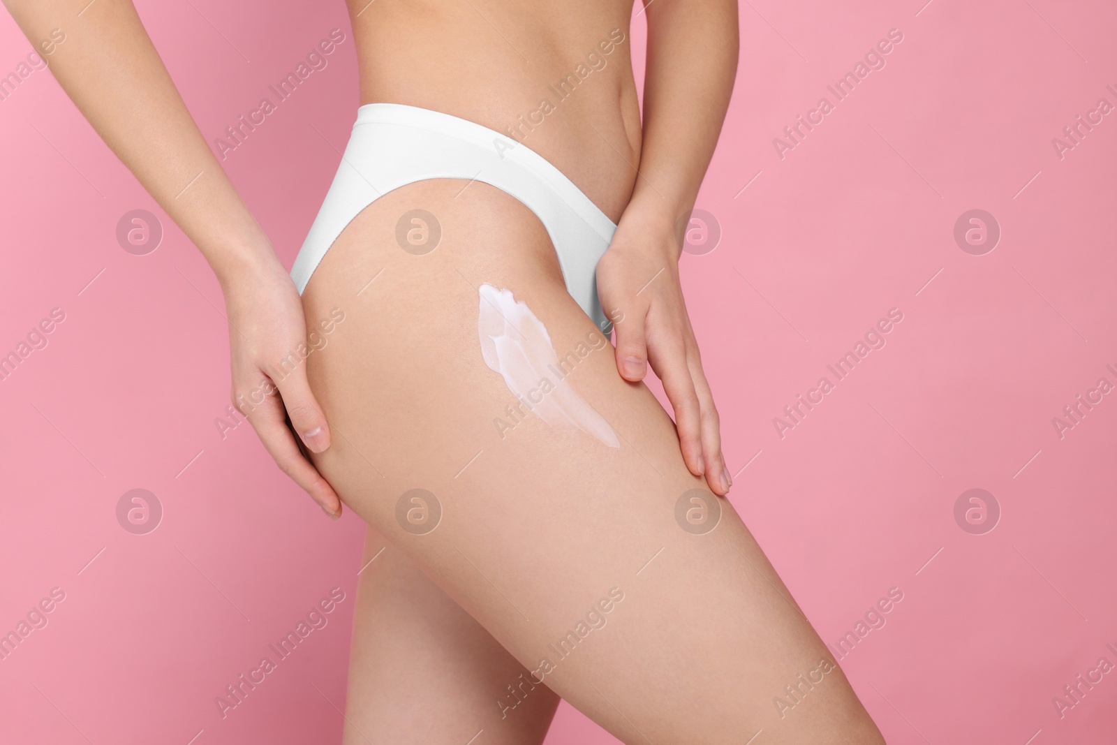 Photo of Woman with smear of body cream on leg against pink background, closeup