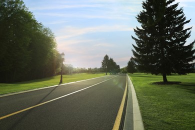 Beautiful view of empty asphalt road and green trees on sunny day