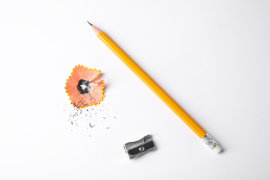 Photo of Graphite pencil, shaving and sharpener on white background, top view