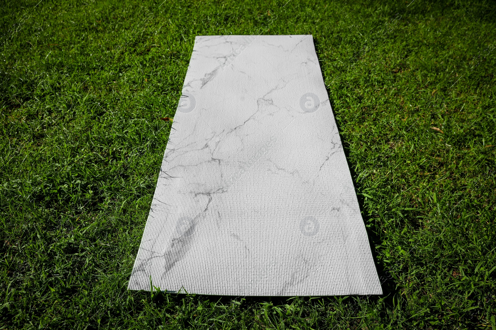 Photo of Karemat or fitness mat on green grass outdoors